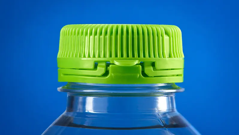 Green tethered bottle cap photographed against a blue background